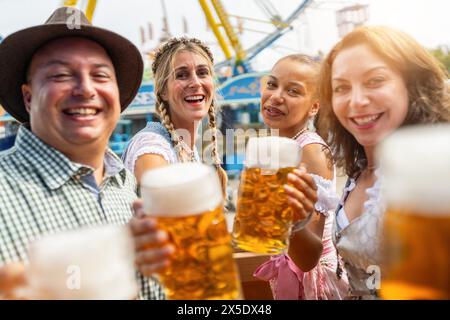 Quatre amis grillent gaiement avec de grandes tasses à bière lors d'une Oktoberfest ou dult dynamique en allemagne Banque D'Images