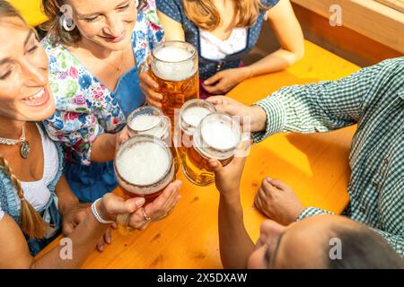 Groupe de personnes dans des tenues bavaroises traditionnelles ou tracht toast avec des steins de bière dans une tente de bière au festival oktoberfest ou dult en allemagne Banque D'Images