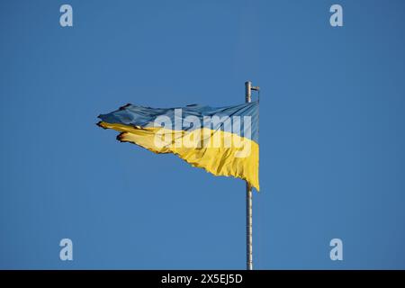 Le drapeau ukrainien brûlé se dresse sur la toile de fond d'un ciel bleu serein : esprit de résilience. Symbole de force et de détermination de la nation ukrainienne a fait face à la tragédie en espérant l'unité, et la poursuite de la liberté Banque D'Images