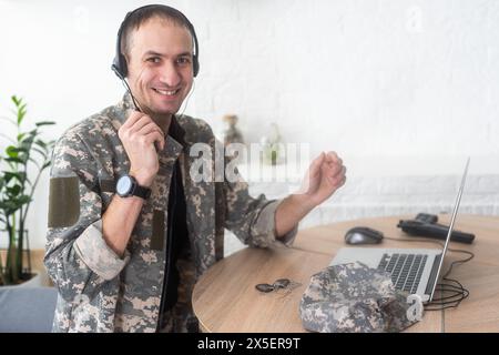 Jeune soldat de l'armée hispanique utilisant un ordinateur portable assis sur une table à la maison Banque D'Images