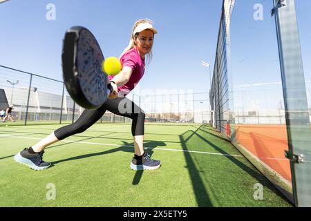 Jeune fille sportive avec raquette jouant au padel dans la cour ouverte à l'extérieur Banque D'Images