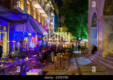 Cafés et boutiques éclairés sur les trottoirs la nuit dans le quartier animé de Monastiraki près de la place Syntagma à Athènes en Grèce. Banque D'Images