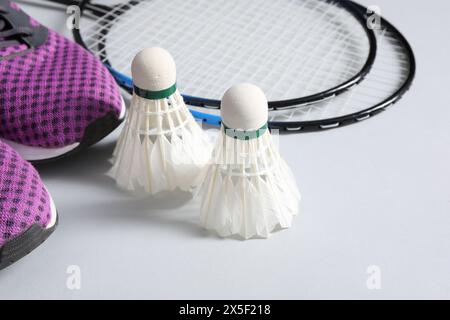 Volants de badminton en plume, raquettes et baskets sur fond gris Banque D'Images