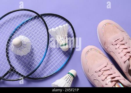 Volants de badminton en plume, raquettes et baskets sur fond violet, pose à plat Banque D'Images