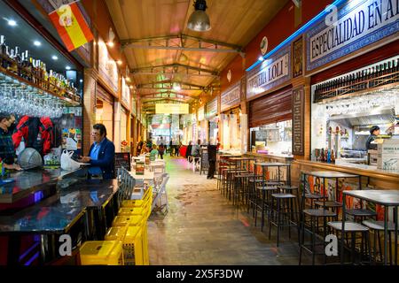 À l'intérieur du marché Mercado Triana plein d'épiceries, de boucheries et d'étals gastronomiques et de cafés dans le quartier de Triana en Andalousie, en Espagne. Banque D'Images