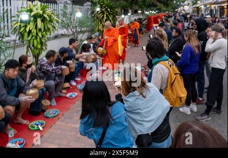 Les touristes prennent des photos de moines lors de la cérémonie des Alms du matin, Luang Prabang, Laos Banque D'Images