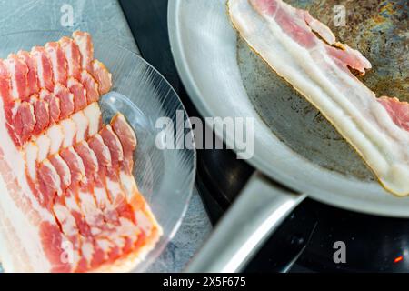 Bacon sur une assiette, préparé pour la poêle. Un morceau de bacon dans une casserole. Délicieuse malbouffe. Photo de haute qualité Banque D'Images