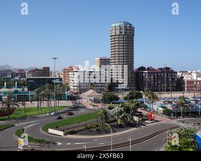 Las Palmas, Espagne - 23 janvier 2024 : vue surélevée sur la route avec circulation, palmiers et bâtiment hôtelier dans la zone portuaire. Personnes visibles dans le parc et sur stre Banque D'Images