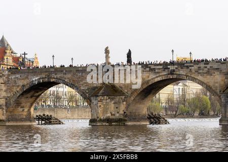 Prague, république tchèque - 3 mars 2024 : touristes marchant sur le pont Charles vu ci-dessous de la rivière Vltava Banque D'Images