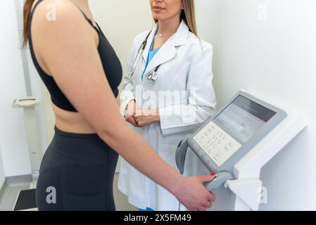 Médecin féminin mesurant la composition corporelle du patient avec un équipement médical avancé Banque D'Images