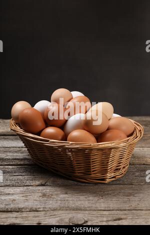 Oeufs de poule frais dans un panier en osier sur une table en bois Banque D'Images