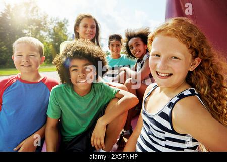 Enfants, groupe et portrait sur aire de jeux dans le parc pour se détendre avec des amis en été en vacances. Heureux, vacances et les enfants ensemble pour le camp, les jeux ou Banque D'Images
