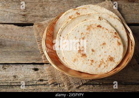 Tortillas maison savoureuses dans un panier en osier sur une table en bois, espace pour le texte Banque D'Images