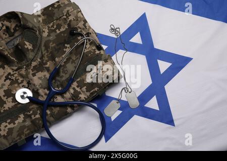 Stéthoscope, tags et uniforme militaire sur le drapeau d'Israël, plat Banque D'Images