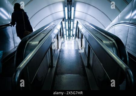 Femme dans l'escalator souterrain de Londres Banque D'Images