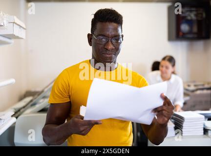Portrait d'un employé positif de la maison d'impression avec des projets entre les mains Banque D'Images