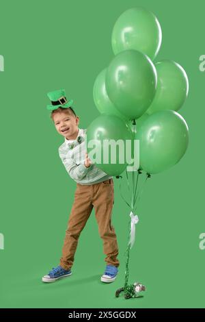 Mignon petit garçon avec chapeau de leprechaun et ballons sur fond vert. Prog Célébration de la fête de Patrick Banque D'Images