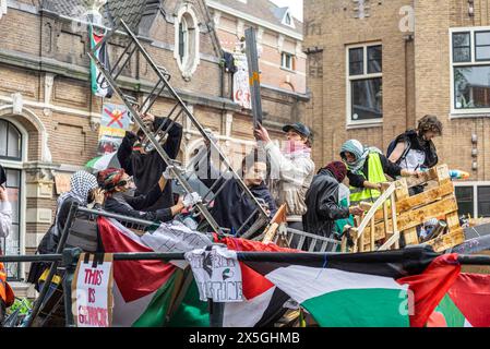 Étudiants et supporters renforcent la barricade, pendant l'occupation du campus de l'Université d'Amsterdam. Étudiants et sympathisants occupent l'Université d'Amsterdam, en solidarité avec le peuple palestinien. Ils avaient également une liste de demandes pour ceux qui gouvernent l'université et ils les accusent de génocide en leur soutien à l'Israël. Le groupe d'action climatique "extinction Rebellion" a également participé. Les barricades ont ensuite été démantelées lors d'une démonstration de force par la police et enfoncées au bulldozer dans un canal voisin. Des manifestations ont également eu lieu à l'Université d'Utrecht, également aux pays-Bas. Pendant ce temps th Banque D'Images