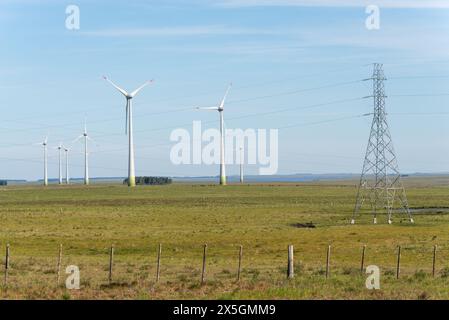 Un champ avec une grande tour de puissance en arrière-plan. Le champ est plein d'éoliennes. Le ciel est clair et bleu Banque D'Images