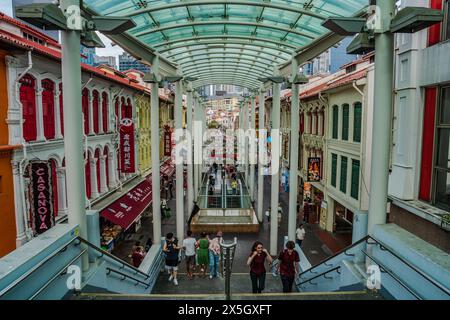 Cette image capture une arcade animée dans un cadre urbain, avec des façades colorées de style colonial sous un revêtement moderne, avec des piétons agréables Banque D'Images