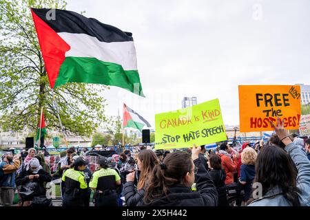 Un drapeau palestinien géant est agité pendant que les manifestants pro-israéliens tiennent des pancartes pendant la manifestation. Manifestants pro-palestiniens et pro-israéliens à l'Université de Toronto devant le camp étudiant occupant King College Circle. Plaidant pour les droits des Palestiniens, les étudiants et les professeurs ont affiché des banderoles illustrant le sort des Palestiniens, des messages anti-sionistes et anti-israéliens, tandis que les manifestations pro-israéliennes ont impliqué des étudiants et des sympathisants en agitant des drapeaux israéliens et en engageant des dialogues pour défendre les actions et les politiques d'Israël. Banque D'Images