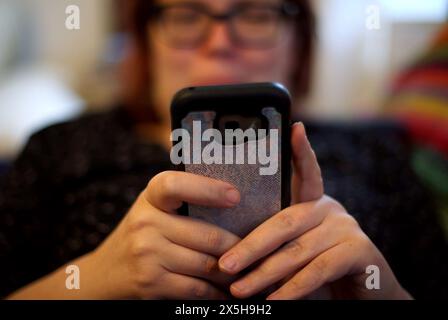 Photo du dossier datée du 08/05/19 d'une femme utilisant son téléphone portable. Les chefs des pompiers et les militants du recyclage ont averti que les incendies causés par les batteries jetées dans les appareils électriques sont en augmentation, causant des dommages et des pics dans les niveaux de pollution de l'air. Selon une étude de Material Focus, qui dirige la campagne Recycle Your Electricals, les incendies de batterie dans les camions-poubelles et sur les sites de déchets ont augmenté de plus de 70 % depuis 2022, avec plus de 1 200 estimés avoir eu lieu l'année dernière. Date d'émission : jeudi 9 mai 2024. Banque D'Images