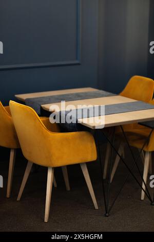 Décor de café contemporain avec chaises jaunes dorées, murs bleus et style minimaliste chic pour une atmosphère détendue. Banque D'Images