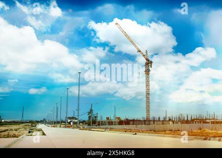 L'exploitant a utilisé la grue à tour sur le chantier de construction pour créer le bâtiment et les condominiums. et le soleil en midi. Banque D'Images