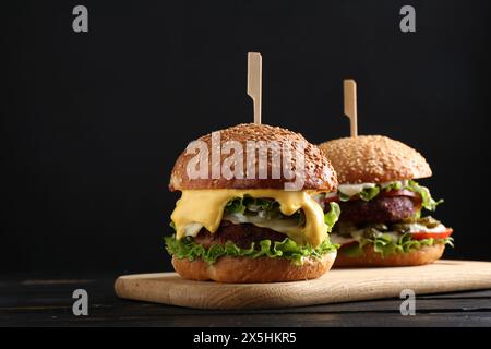 Hamburgers végétariens avec de délicieuses galettes sur une table en bois noir Banque D'Images