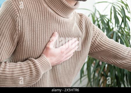 Le jeune homme éprouve une douleur thoracique soudaine derrière le sternum, une poitrine serrée, une hypertension artérielle, une myocardite ou une arythmie, une maladie cardiaque e Banque D'Images