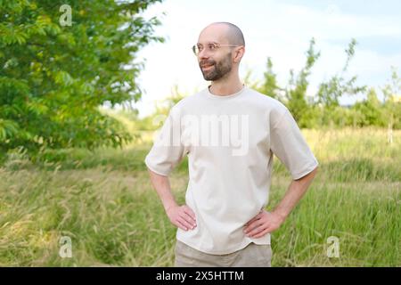 Jeune homme sérieux de 30 ans en plein air dans la nature, sourire subtil sur les lèvres, psychologie et impact, sérieux et détermination, santé mentale en troisième D. Banque D'Images