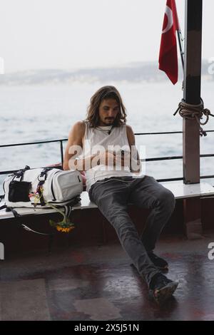Un jeune homme touriste avec un sac à dos monte sur un vapur à Istanbul. Banque D'Images