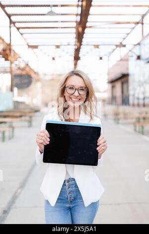 Femme souriante tenant la tablette en milieu urbain Banque D'Images