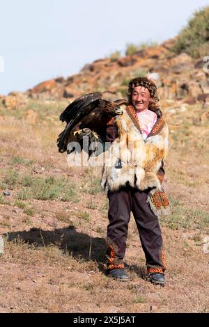 Asie, Mongolie, Province de Bayan-Olgii. Altaï Eagle Festival, chasseur d'aigle kazakh en vêtements brodés et en fourrure récupère fièrement son aigle doré. (Usage éditorial uniquement) Banque D'Images
