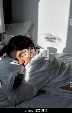 jeune homme aux cheveux noirs dormant profondément dans la chambre, embrassant l'oreiller, a peur. gros plan vue latérale portrait Banque D'Images