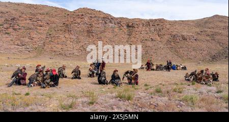 Asie, Mongolie, Province de Bayan-Olgii. Altai Eagle Festival, les chasseurs d'aigle s'assoient ensemble en groupes en attendant le concours auquel ils ont participé. (Usage éditorial uniquement) Banque D'Images