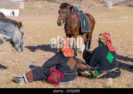 Asie, Mongolie, Province de Bayan-Oglii. Altaï Eagle Festival, les chasseurs d'aigle kazakhs avec leurs chevaux et aigles attendent les résultats du concours. (Usage éditorial uniquement) Banque D'Images