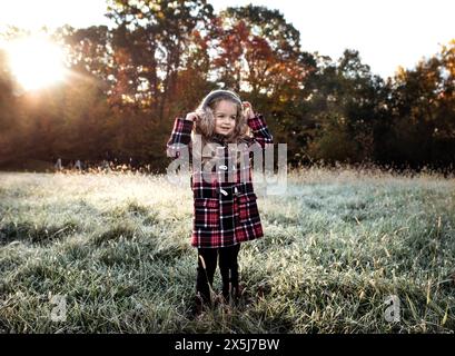 Petite fille heureuse dans le champ givré avec des arbres d'automne colorés Banque D'Images