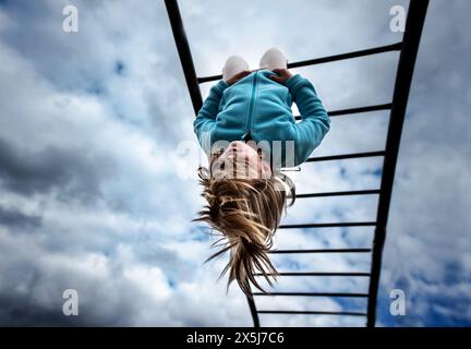 Jeune enfant suspendu à l'aire de jeux de l'école des bars de singe Banque D'Images