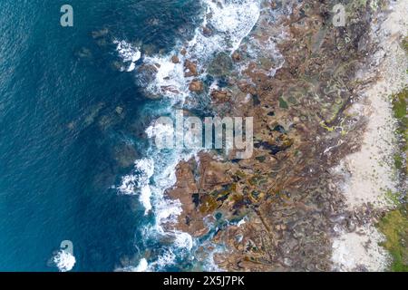 vue aérienne par drone des vagues éclaboussant dans un rivage rocheux Banque D'Images