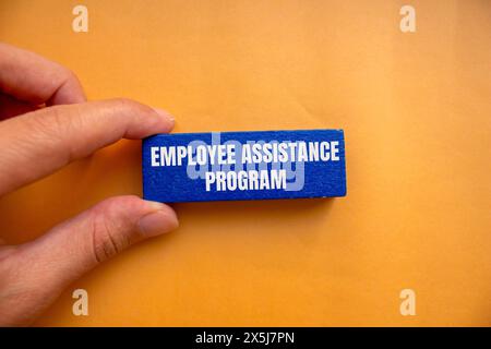 Mots du programme d'aide aux employés écrits sur un bloc de bois bleu sur fond orange. Symbole conceptuel du programme d'aide aux employés. Copier l'espace. Banque D'Images