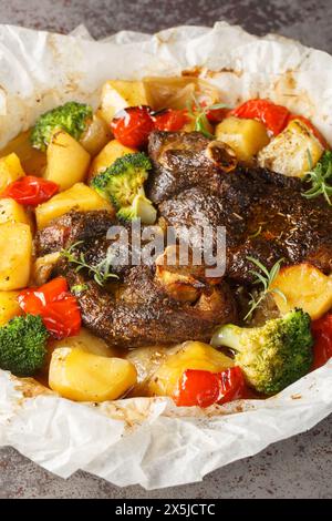 Agneau cuit avec des légumes et des herbes dans le parchemin gros plan dans une poêle sur la table. Vertical Banque D'Images