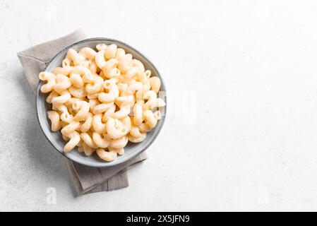 Mac et fromage sur fond de béton blanc, vue de dessus, espace de copie. Bol de pâtes crémeuses Alfredo Cavatappi. Banque D'Images