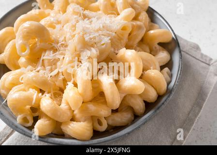 Mac et fromage gros plan. Bol de pâtes crémeuses Alfredo Cavatappi avec parmesan râpé. Banque D'Images