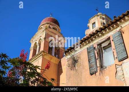 Corfou, Grèce. Église en terre cuite à dôme rouge, volets et bougainvilliers rouges Banque D'Images