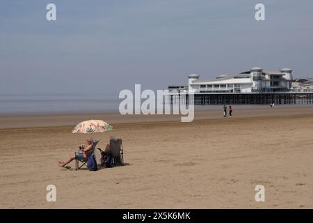 Weston-super-Mare, Royaume-Uni. 10 mai 2024. Les gens profitent d'une journée chaude sur la plage de Weston-super-Mare. Plage très calme et Grand Pier. Crédit : JMF News/Alamy Live News Banque D'Images