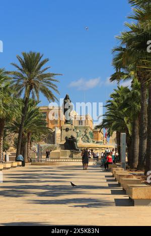 La Valette, Malte. Palmiers, bancs du parc, statues de bronze, fontaine Triton et les gens dans le parc Banque D'Images