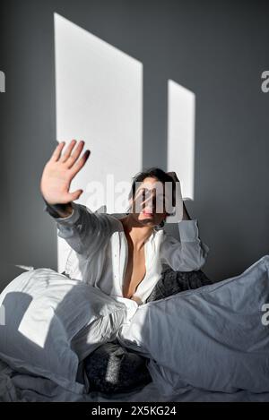 jeune homme levant le bras, regardant sa paume, assis dans la chambre. gros plan portrait Banque D'Images