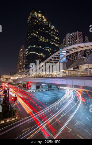 Chong Nonsi Skywalk - passerelle piétonne illuminée, gratte-ciel et embouteillage dans le quartier central des affaires de Bangkok, Thaïlande au crépuscule Banque D'Images