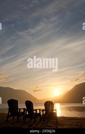 Trois chaises longues en bois de style Adirondack au Crescent Lake Lodge au parc national olympique au coucher du soleil. Banque D'Images